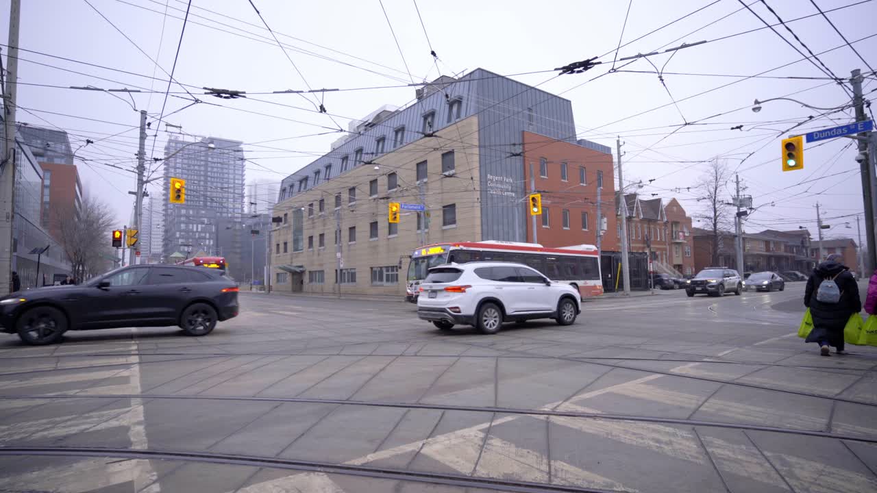 Dundas and Parliament Street Intersection in Toronto, Ontario, Canada. City bus and Street Car TTC Tram at lights as public city transportation and cars passing through green light and stopped at red