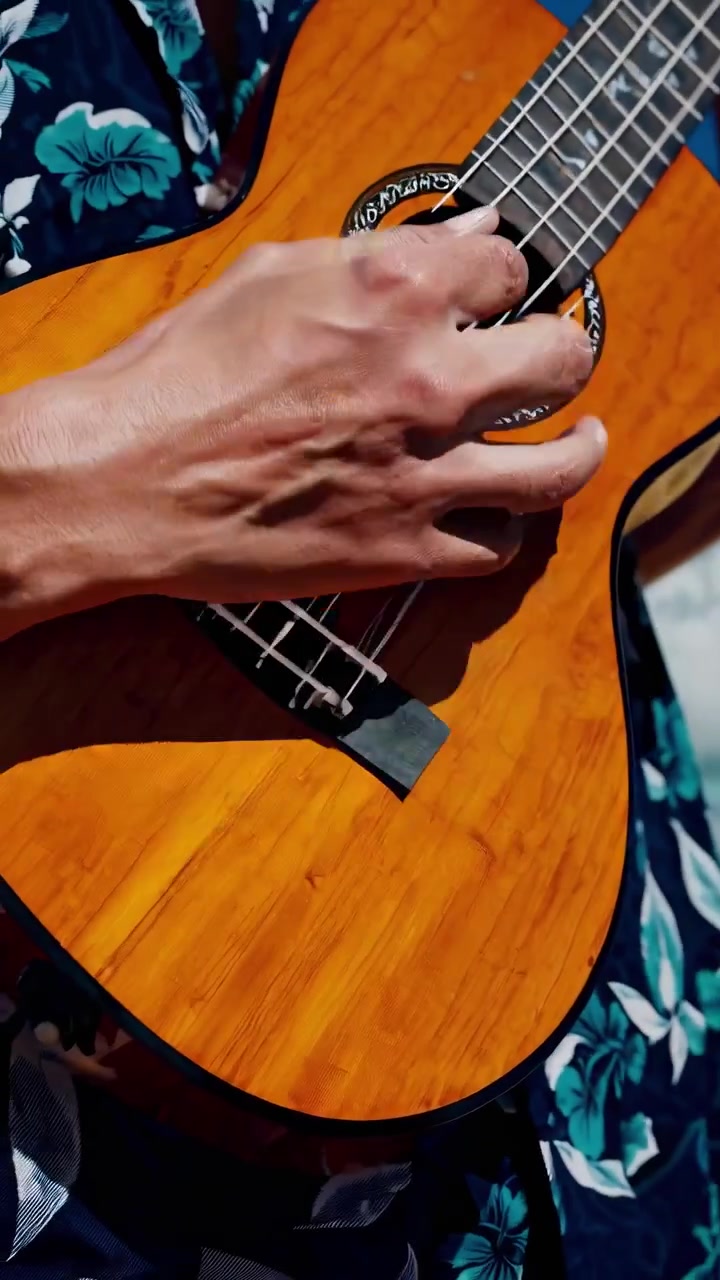 Primo piano di mani che suonano l'ukulele su una spiaggia tropicale