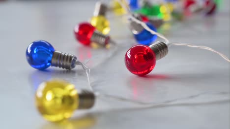 a narrow-focused view of christmas led lights in blue, red, yellow, and green is visible on a white surface