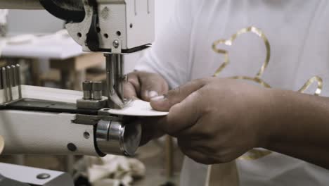 a man uses a sewing machine to stitch fabrics in a factory