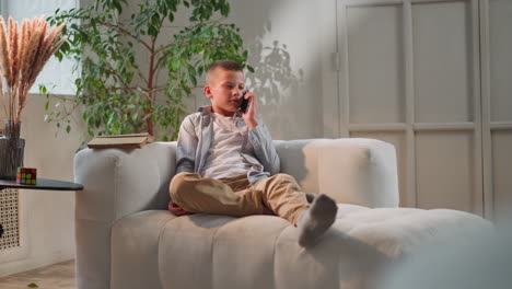 niño molesto escucha la voz de la madre sosteniendo el teléfono móvil cerca de la oreja