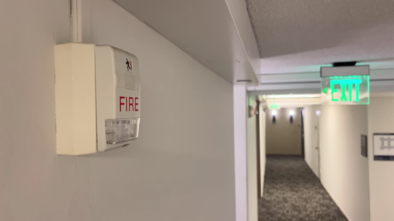 Fire Alarm and Green Exit Sign in Building Corridor