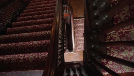 looking down an old staircase in a 1900's mansion with red carpet steps