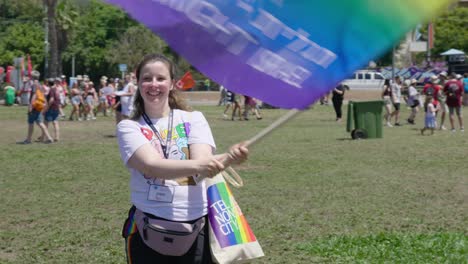 a beautiful woman was standing in a field waving a flag. she was very happy and enjoying the parade