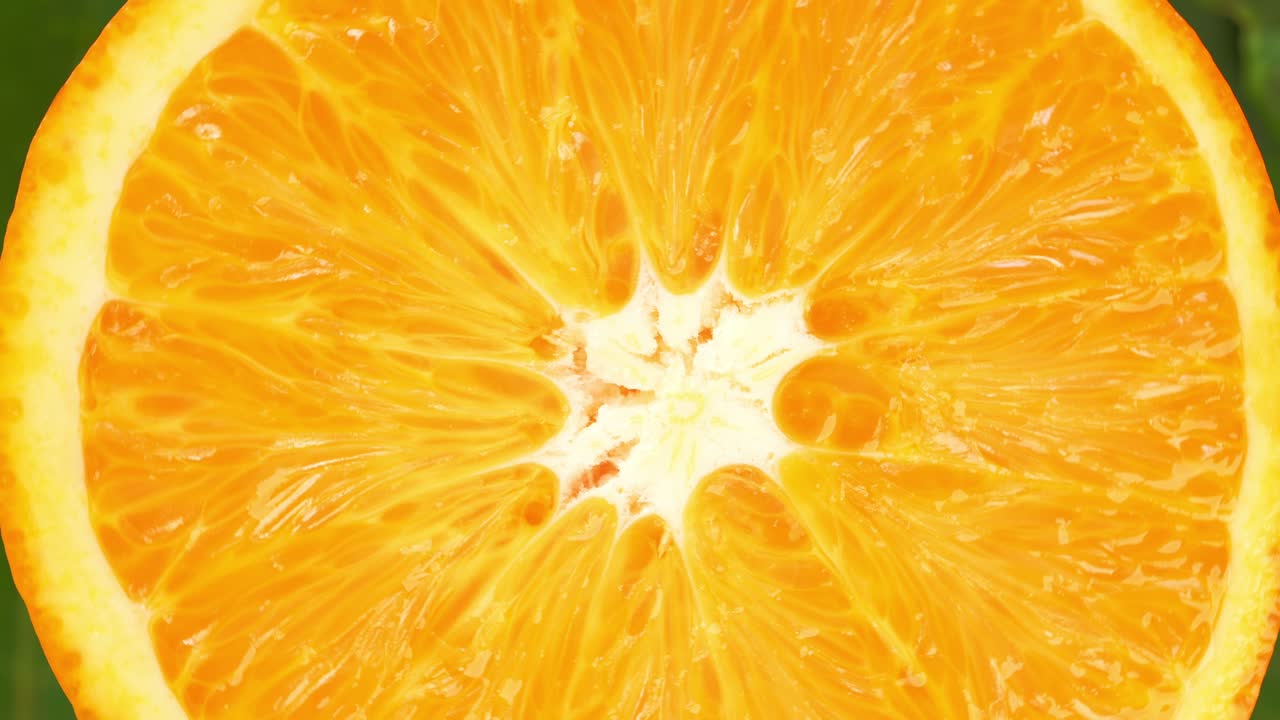 vista superior girar la rebanada de naranja en hojas verdes de fondo, cerrar la naranja fresca cortada en fondo blanco y girar lentamente.