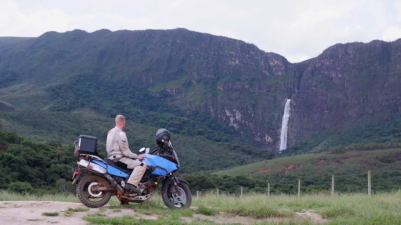 Caucasian man on motorcycle enjoys view of distant Casca D'anta falls