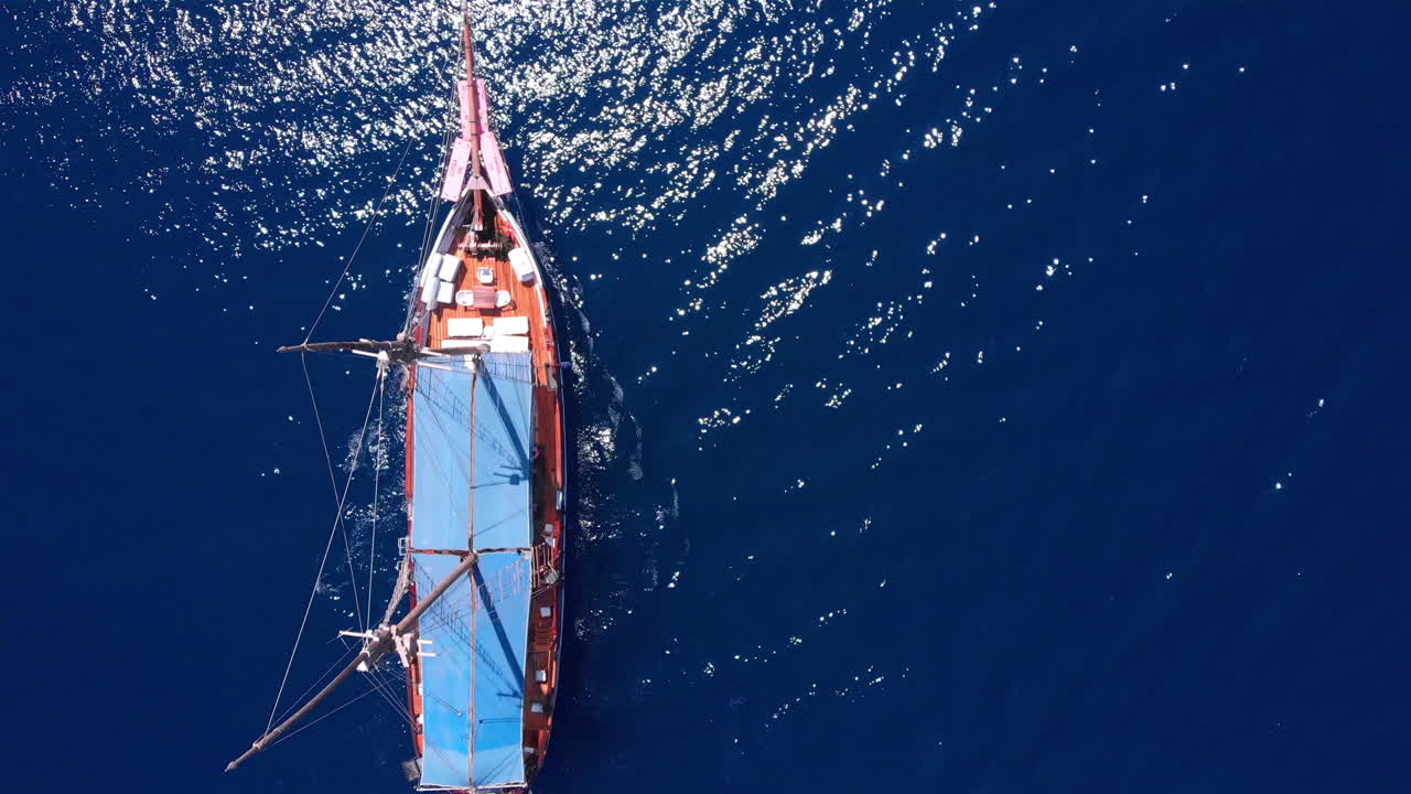 Tourists tour on old style pirate ship on calm clear drak blue sea Aerial top down view