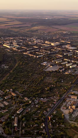 aerial footage over small town in nature. flight over the small buildings among fields in summer. aerial view. vertical video