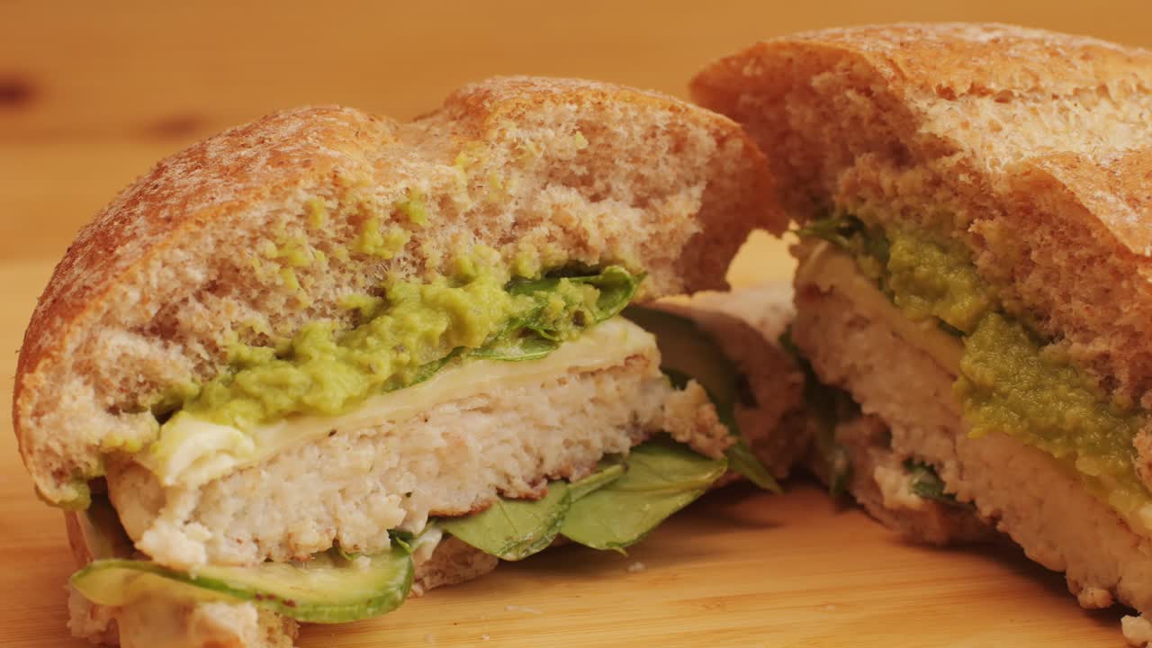 American burger with fish or chiken cutlet, with green salad,onion and guacamole on top close-up. Chef makes burgers without meet. Fast and street food concept. High quality 4k footage