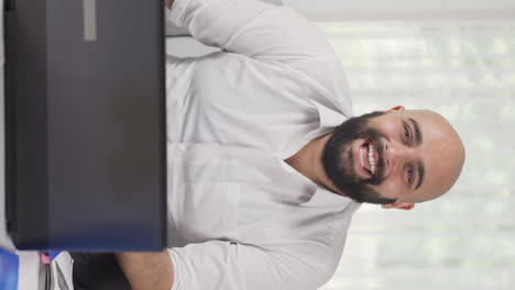 Vertical-video-of-Home-office-worker-man-smiles-at-camera.