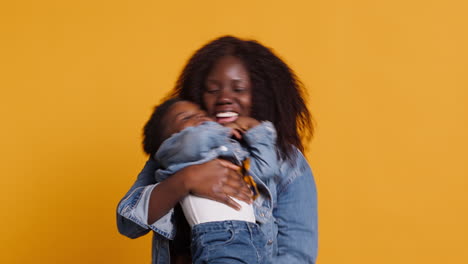 Smiling-african-american-mom-carrying-her-sweet-little-boy-in-studio