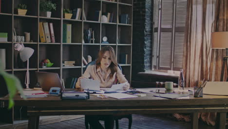 mujer de negocios atractiva leyendo gráficos en documentos en el lugar de trabajo