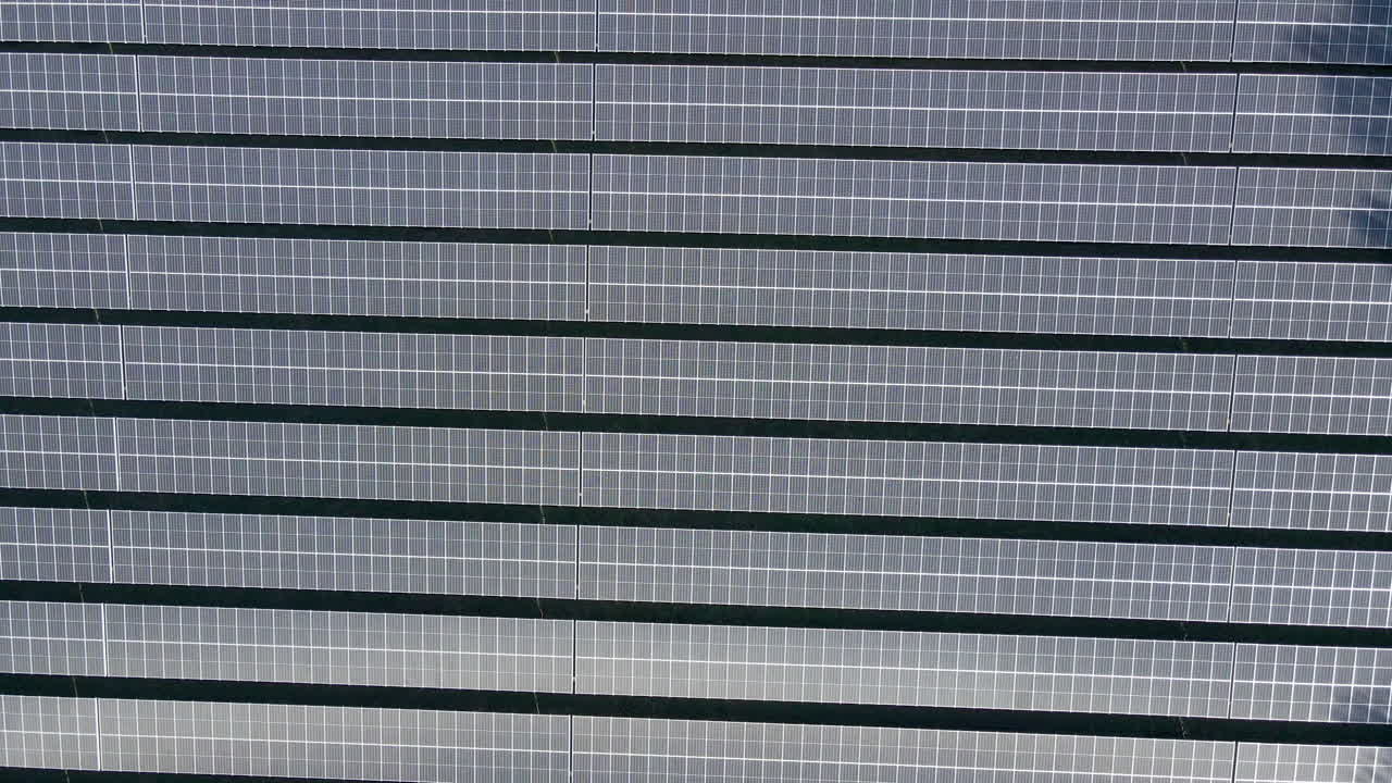 antena de arriba hacia abajo de largas filas de paneles fotovoltaicos en un gran campo de paneles solares