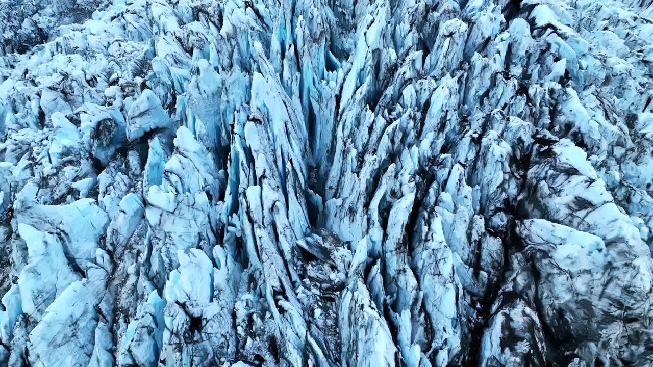 A dramatic establishing aerial shot revealing deep ice fractures and ...