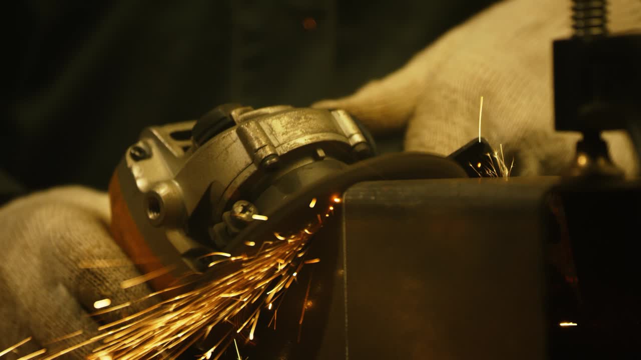 рабочий шлифовал железо. интерьер завода тяжелой промышленности с рабочим, использующим угловой шлифователь с большим количеством острых искр. электрическое колесо шлифовало на стальной трубе на заводе. медленное движение. 4k видео. снято на красном