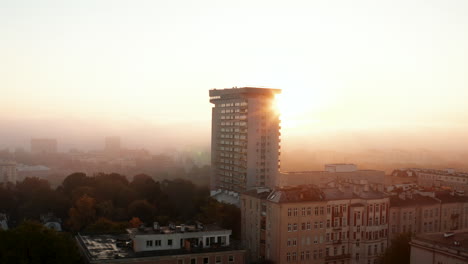 Diapositiva-Y-Toma-Panorámica-De-Un-Edificio-De-Apartamentos-Que-Se-Eleva-Sobre-El-Desarrollo-De-Otra-Ciudad.-Alto-Prefabricado-Contra-El-Sol-Saliendo-Detrás-De-La-Niebla.-Varsovia,-Polonia