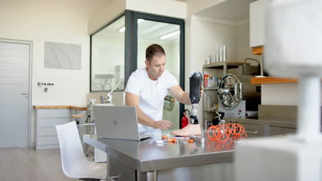 working in prosthetic lab, man adjusting prosthetic limb with tools on table