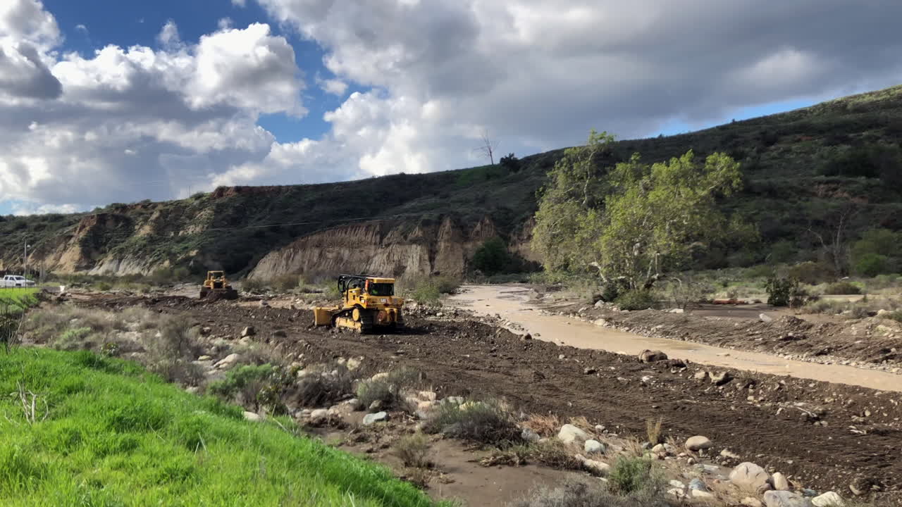 Bulldozere udjævner i et flodleje efter en storm, der skyllede vejen væk. Vinkel 4.