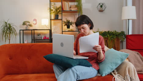 Erschöpfte-Freiberufliche-Frau-Mit-Papierkram,-Die-Zu-Hause-Einen-Laptop-Benutzt-Und-Dokumente-In-Die-Luft-Wirft