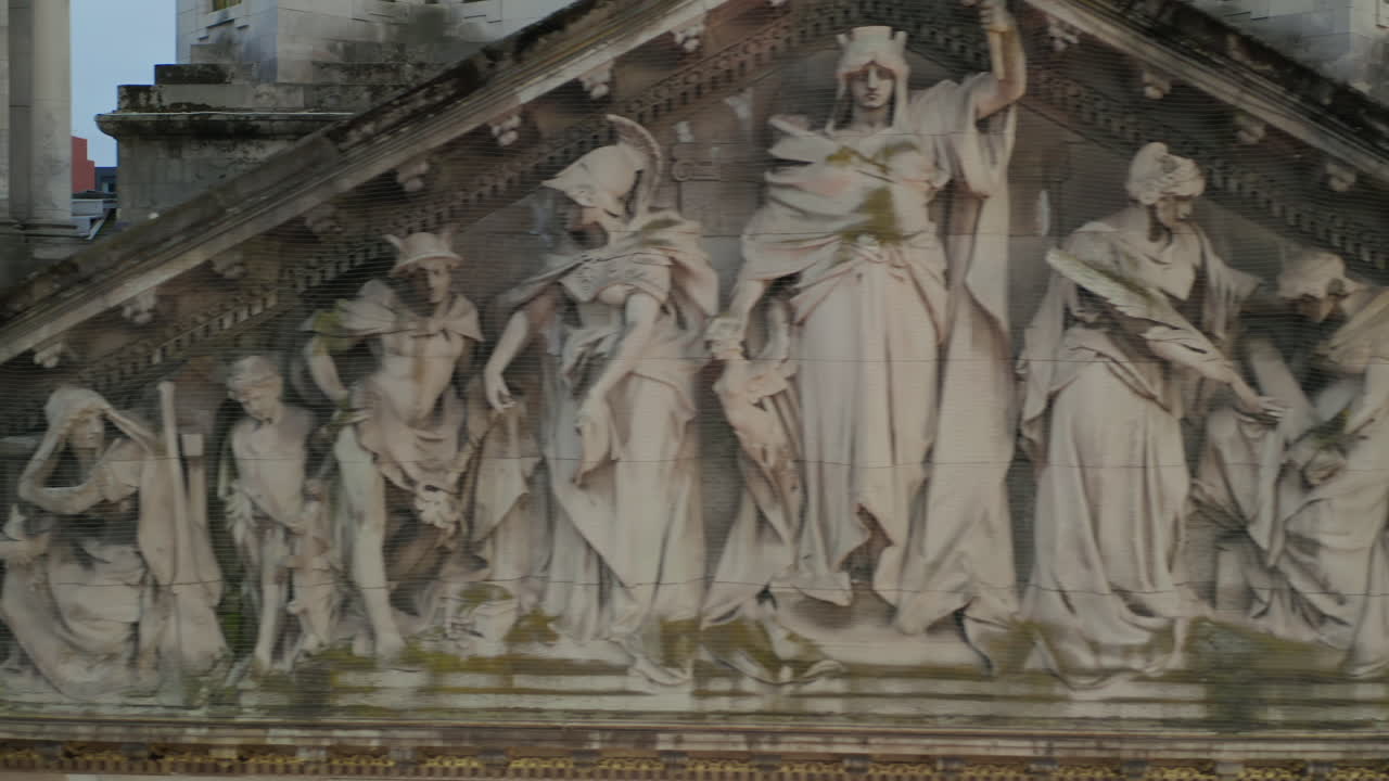 Drone tracking sideways across allegorical stone reliefs depicting "Hibernia" in Belfast City Hall's pediment