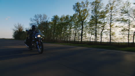 biker on a motorcycle through the trees the sun shines