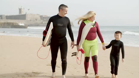 familia feliz con tabla de surf caminando por la playa
