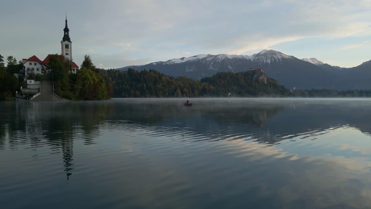 Vista aerea del Lago di Bled con la chiesa sull'isola e una barca a remi all'alba