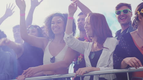 group of young friends dancing behind barrier at outdoor music festival