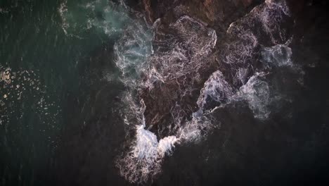 waves breaking on rocks in california - birds-eye view