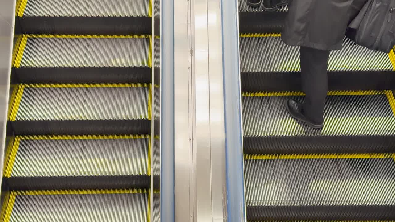 Højt vinkelbillede af mennesker i vinterfrakker, der kører på en rulletrappe på en japansk station.