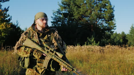 a man in a camouflage bandanna and walking along a country road in the hands holding weapons slow mo