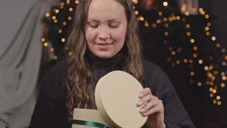 woman receives round christmas holiday gift opens it with disappointment to hand back to giver