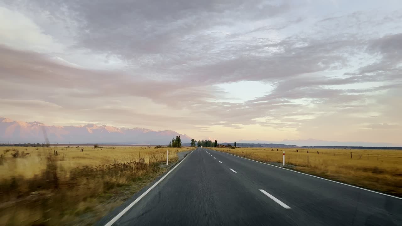 Stunning road trip along New Zealand's countryside highways with mountains in background at sunrise
