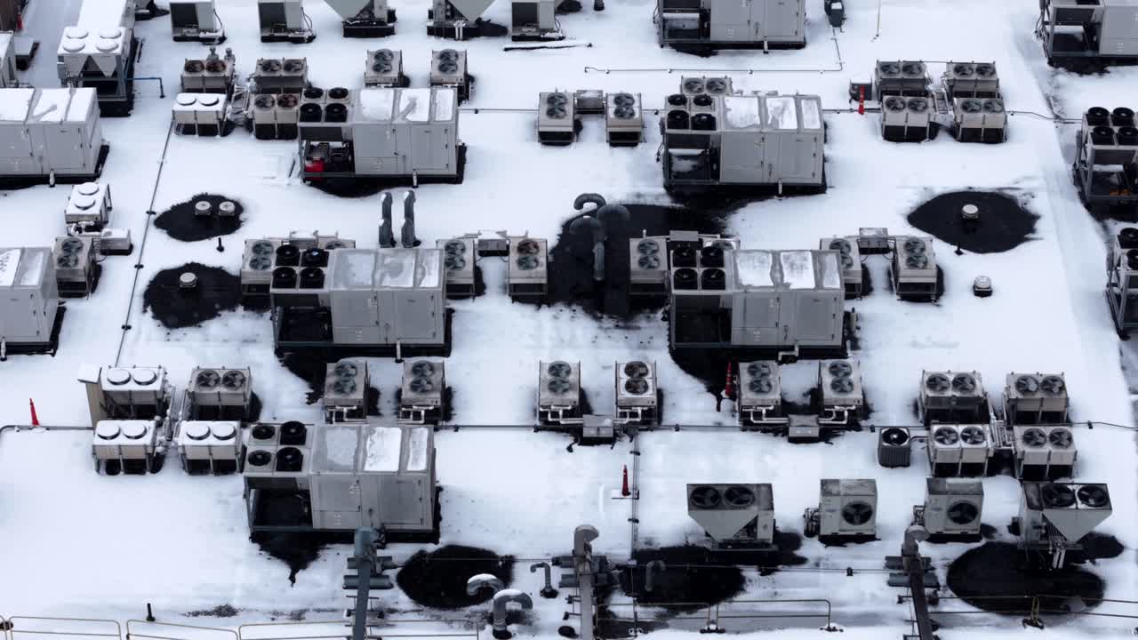 Panning drone fly of heating, ventilation, and air conditioning system in snow-covered rooftop area
