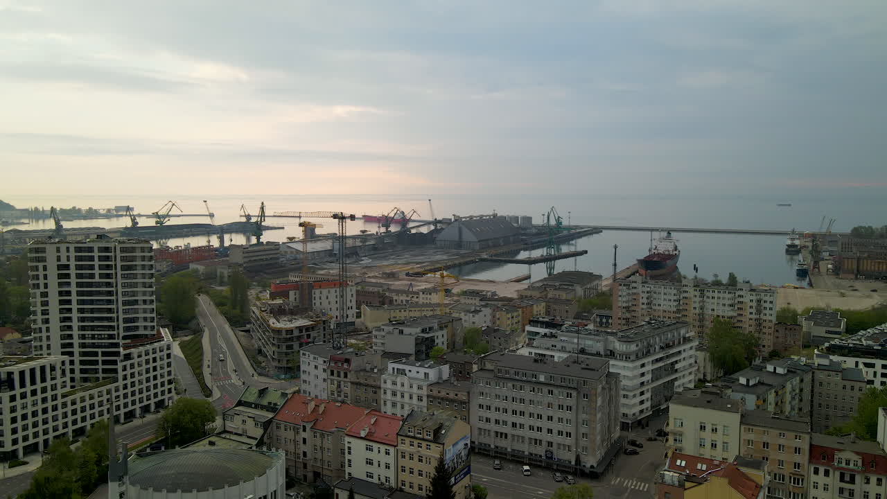Panorama aereo del porto di Gdynia e del quartiere residenziale al tramonto nuvoloso, con il terminal portuale per container marittimi sullo sfondo