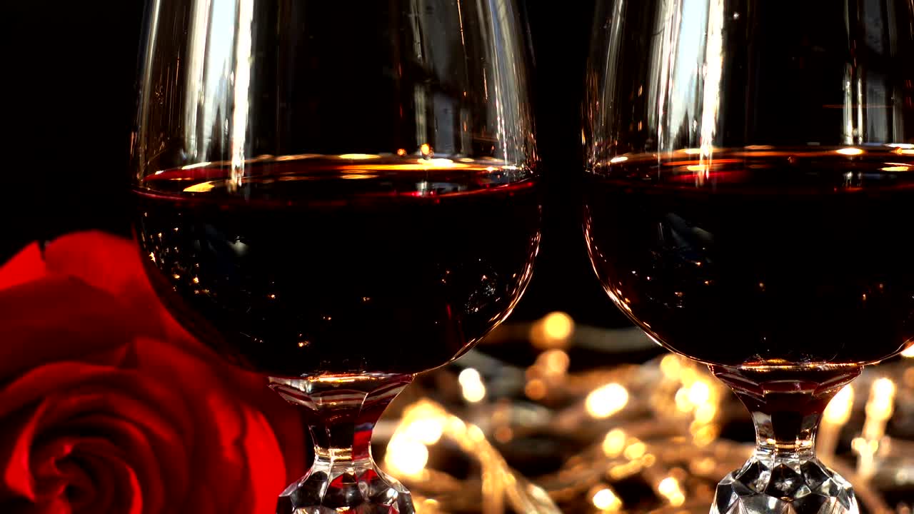 Taças de vinho e rosa contra o fundo de guirlandas brilhantes