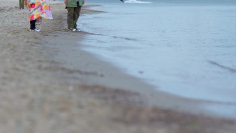 people standing on pebbled beach watching calm waves in 4k