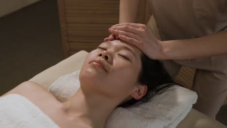 woman receiving a relaxing head and face massage at a spa