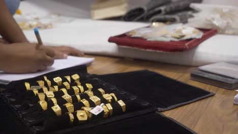 a shopkeeper making counts of hallmarked designer gold jewelry, wedding rings