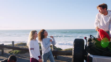 young adult friends unloading backpacks from the back of car