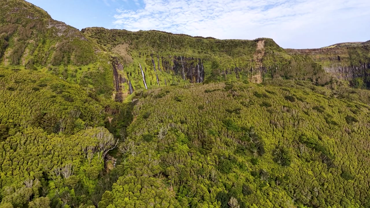 Rivelazione cinematografica di cascate che emergono attraverso le verdi scogliere vulcaniche a Poco da Ribeira do Ferreiro nelle Azzorre, Portogallo.