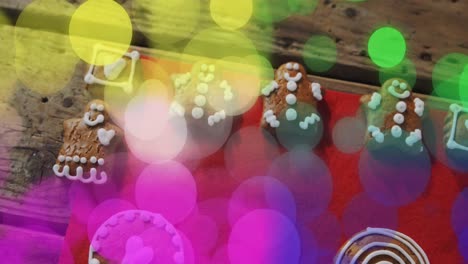 animation of yellow, green and pink light spots over christmas gingerbread men and cookies