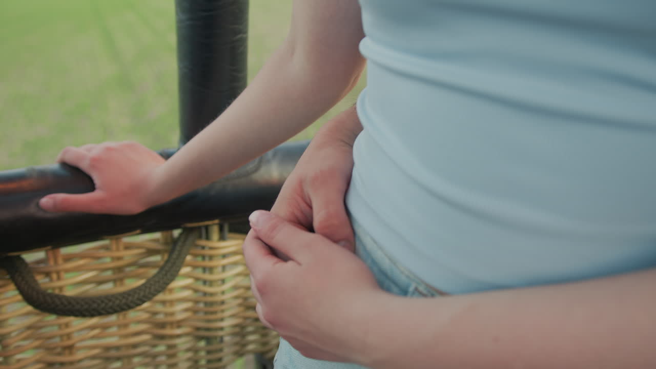 close up of couple embracing intimately in moving hot air balloon above wide green farmland as hand rests gently on waist expressing warmth and romance during peaceful sunset countryside flight