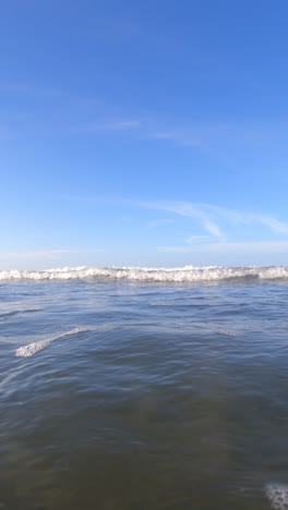 waves crashing over the camera on a beautiful, sunny day at the beach