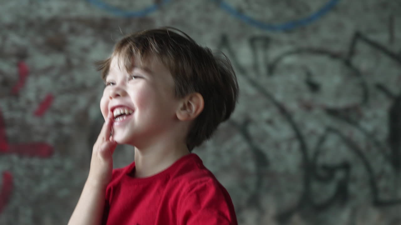 Video en cámara lenta de un niño pequeño con una camiseta roja, muy emocionado y riendo de alegría.