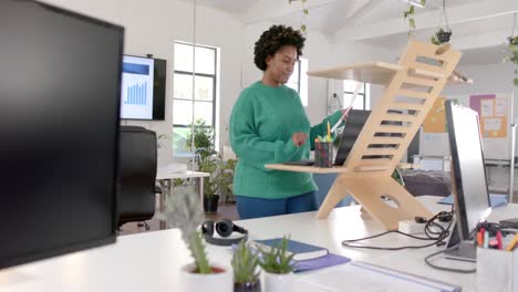 happy african american casual businesswoman using laptop in office, slow motion