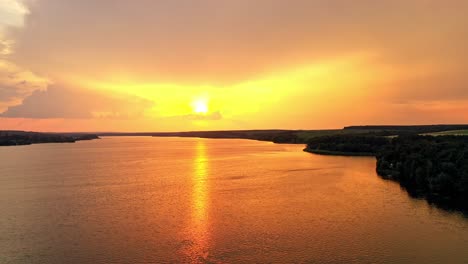 beautiful orange sunset over the calm river. natural landscape of green forest and river in the evening. aerial view. camera moves left.