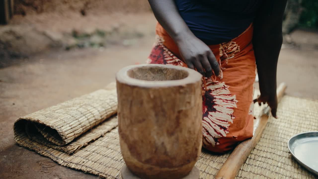 Roasted coffee beans dropped from metal plate into wooden mortar for grinding