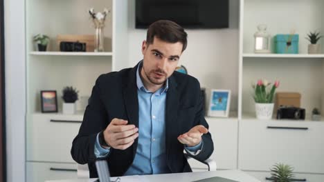 Portrait-of-a-confident-man-in-business-clothes-gesturing-and-showing-graphs-of-financial-growth-and-investment-in-a-solid-office