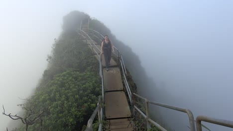 young woman walks through cloud, high on the haiku stairs